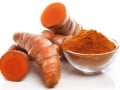 fresh turmeric root and a glass bowl of turmeric powder