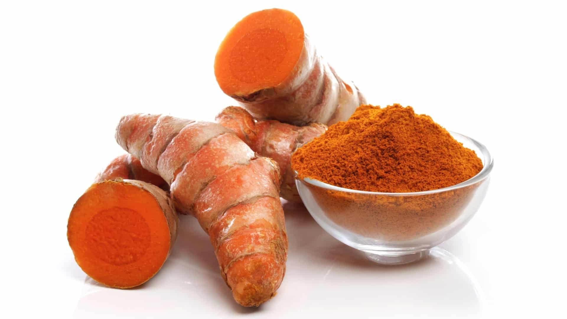 fresh turmeric root and a glass bowl of turmeric powder